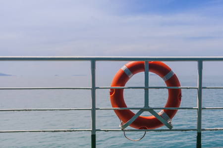 Red Lifebuoy in front of the blue sea and the ferry.の写真素材