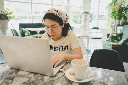 Woman using laptop while sitting at cafe.の写真素材