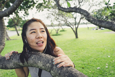 Beautiful girl posing behind the tree in the park.の写真素材