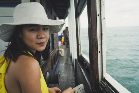 Portrait of young woman wearing yellow dress sitting on the boat.の写真素材
