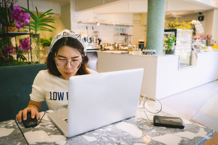 Woman using laptop while sitting at cafe.の写真素材