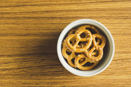 Mini pretzels in white bowl on the wooden table.の写真素材