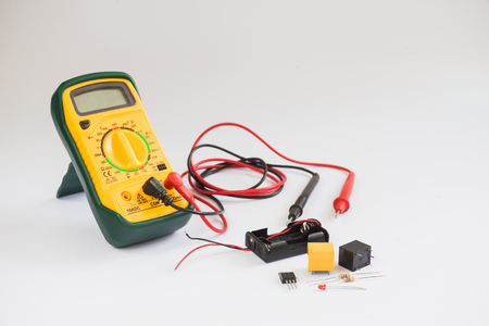Electrical multimeter and electronic component on white background.