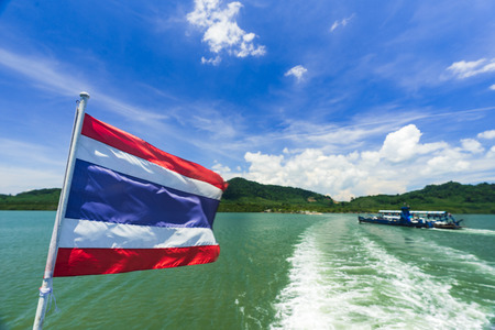 Flag of Thailand on a ship in the Andaman sea with blurred ferry in the background.の写真素材