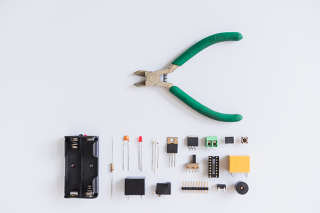 Top view of pliers and electronics component such as resistor, ICs, capacitor, switch, and connector on white background.の写真素材