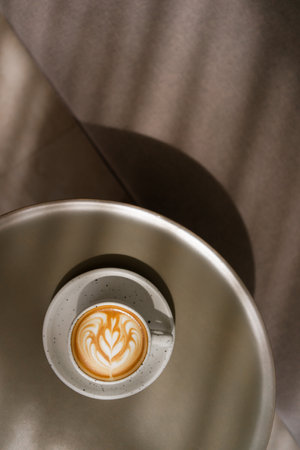 Cup of coffee latte on table and beautiful latte art with afternoon light in the cafe.