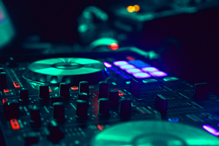 dj mixer with green tones in night club