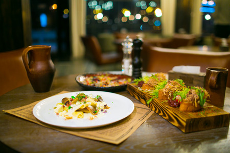 Crepe mushrooms and meat appetizers on wooden cutting board. Hearty meal in the evening
