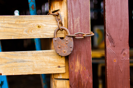 Old padlock attached to the wooden wall of shed with metal chain. Shed for storing gardening toolsの写真素材