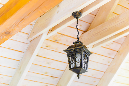 Old metal light hanging on wooden planks close-upの写真素材