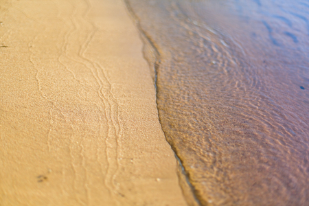 Sandy beach washed by quiet rippling waveの写真素材