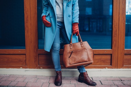 Beauty and fashion. Stylish fashionable woman wearing coat and gloves ,holding brown bag handbag.の写真素材