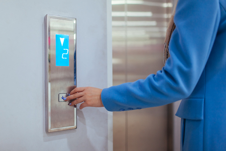 Woman Standing In Elevator And Pressing Button.