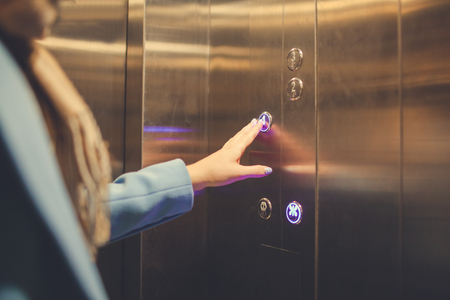 Woman Standing In Elevator And Pressing Button.