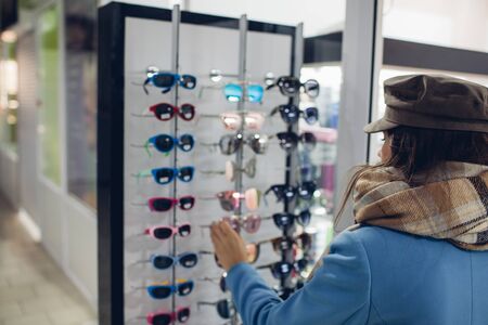 Young Woman in Optical Store - Beautiful girl chooses glasses in optician shopの写真素材