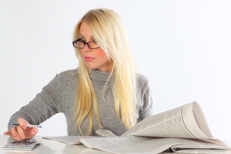 The business woman wearing spectacles with newspapers and the laptop works behind a table  の写真素材