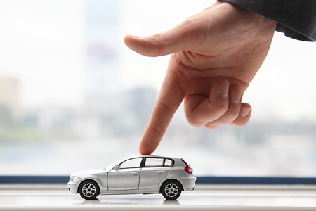 The finger of the businessman moves the toy car