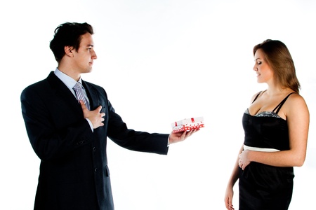 Young handsome man giving a young beautiful girl, a red box with a red bow on topの写真素材