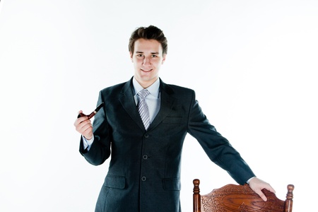 Portrait of a young handsome man in a dark suit with a strict smoking a pipe in his handの写真素材