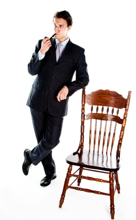 Portrait of a young handsome man in a dark suit with a strict smoking a pipe in his handの写真素材