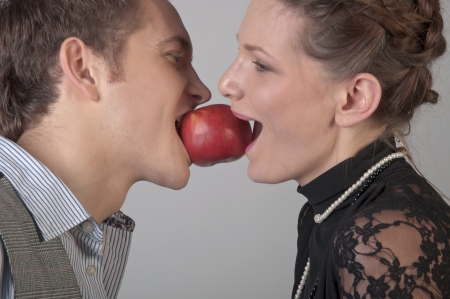 girl and young man bite together red appleの写真素材