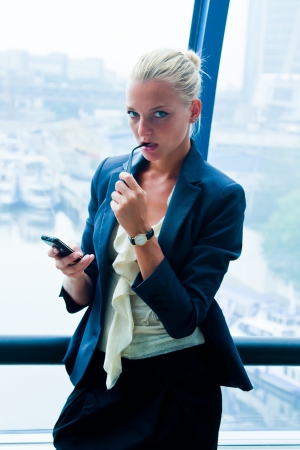 Young and beautiful business woman reading sms message on mobile phoneの写真素材