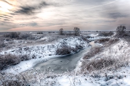 winter landscape with a river and a few treesの写真素材