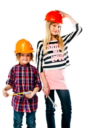 Two young beautiful girls in building helmet and tools in handの写真素材