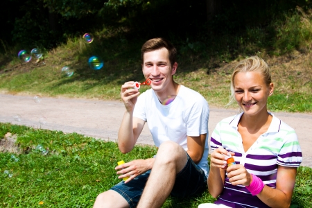 young and beautiful man and woman blow bubblesの写真素材