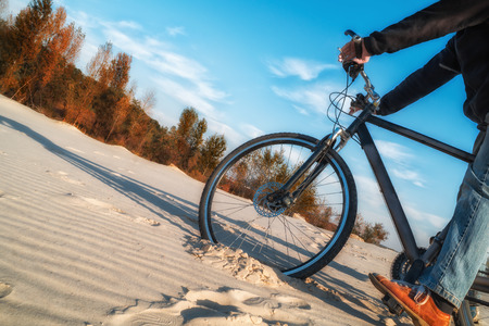 bicycle wheel in the sand goes up the hillの写真素材