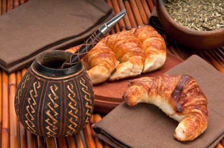 Calabash cup for mate and croissants, with yerba mate in the foreground. Mate is a very popular tradition in Argentina and Uruguay.の写真素材