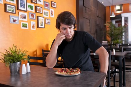 Young man seated in a bar very worried and pensive.の写真素材