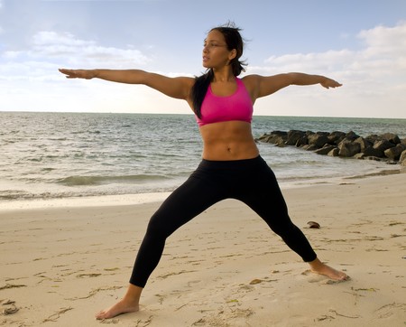 Young woman practices yoga early morning in the beach.の写真素材