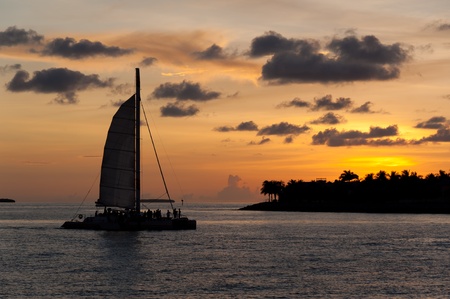 Catamaran sailing with tourists with a caribbean island behind at sunset.の写真素材