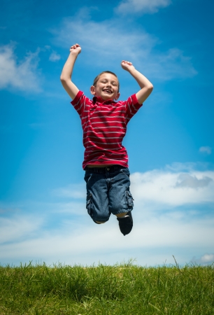 6 years old boy jumping very happy in a park during summertimeの写真素材