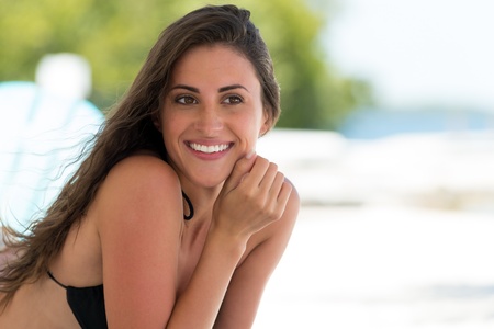 Upper body portrait of a beautiful smiling woman in a bikini with a high key beach backgroundの写真素材