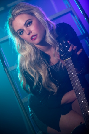 Blonde woman holding electric guitar in a backstageの写真素材