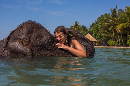 Girl swims with the elephant in the blue sea-ocean in Thailandの写真素材