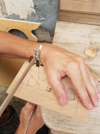 A carpenter cuts a workpiece out of wood with a jigsawの写真素材