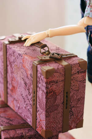 The doll is holding a miniature doll suitcaseの写真素材