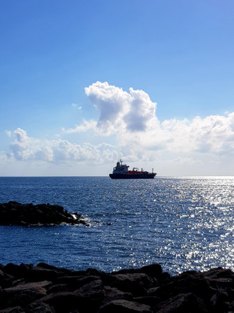 Seascape with cargo ship in the sea and blue sky.