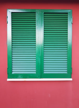 Green window shutters on red wall, vintage and retro style.の写真素材