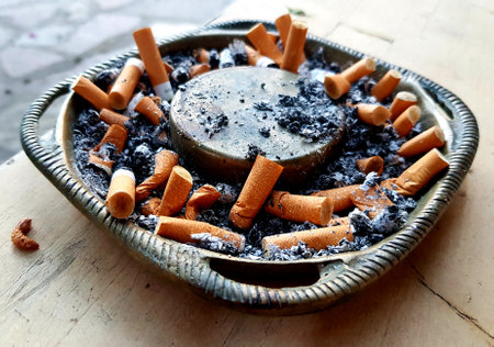 Cigarette butts in ashtray on wooden table.の写真素材