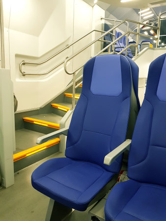 Interior of a modern train with blue seats and stairs, closeup photo