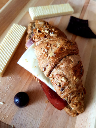 Croissant sandwich with cheese, ham, tomato and raisinsの写真素材
