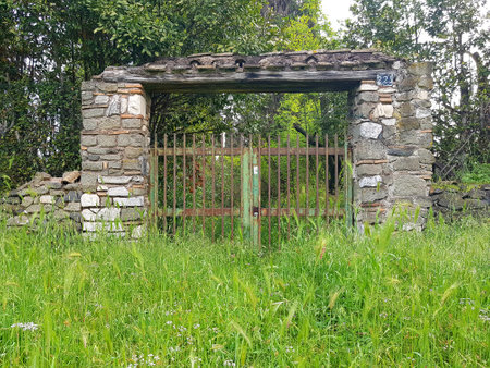 Old gate in a meadow with green grass and a stone wallの写真素材