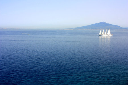 A white yacht sails in the Mediterranean Sea with Vesuvius in the backgroundの写真素材