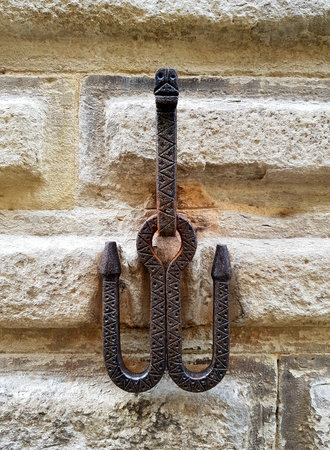 Antique iron hitching post for horses on the wall of an old house in Siena, Italy