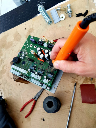 Repairing a circuit board with a soldering iron in a workshop