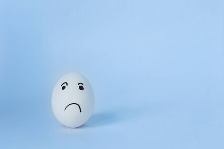 A one white chicken egg in a medical mask isolated on blue background. Protection Concepts with Corona Virus (COVID19). Easter eggs in a mask. Safety comes first during Easter 2020.の写真素材